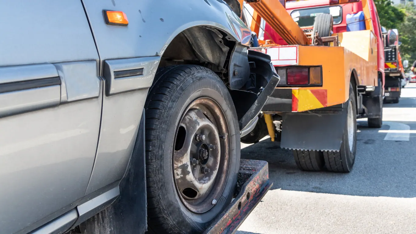 Tow truck lifting a car with front-end collision damage