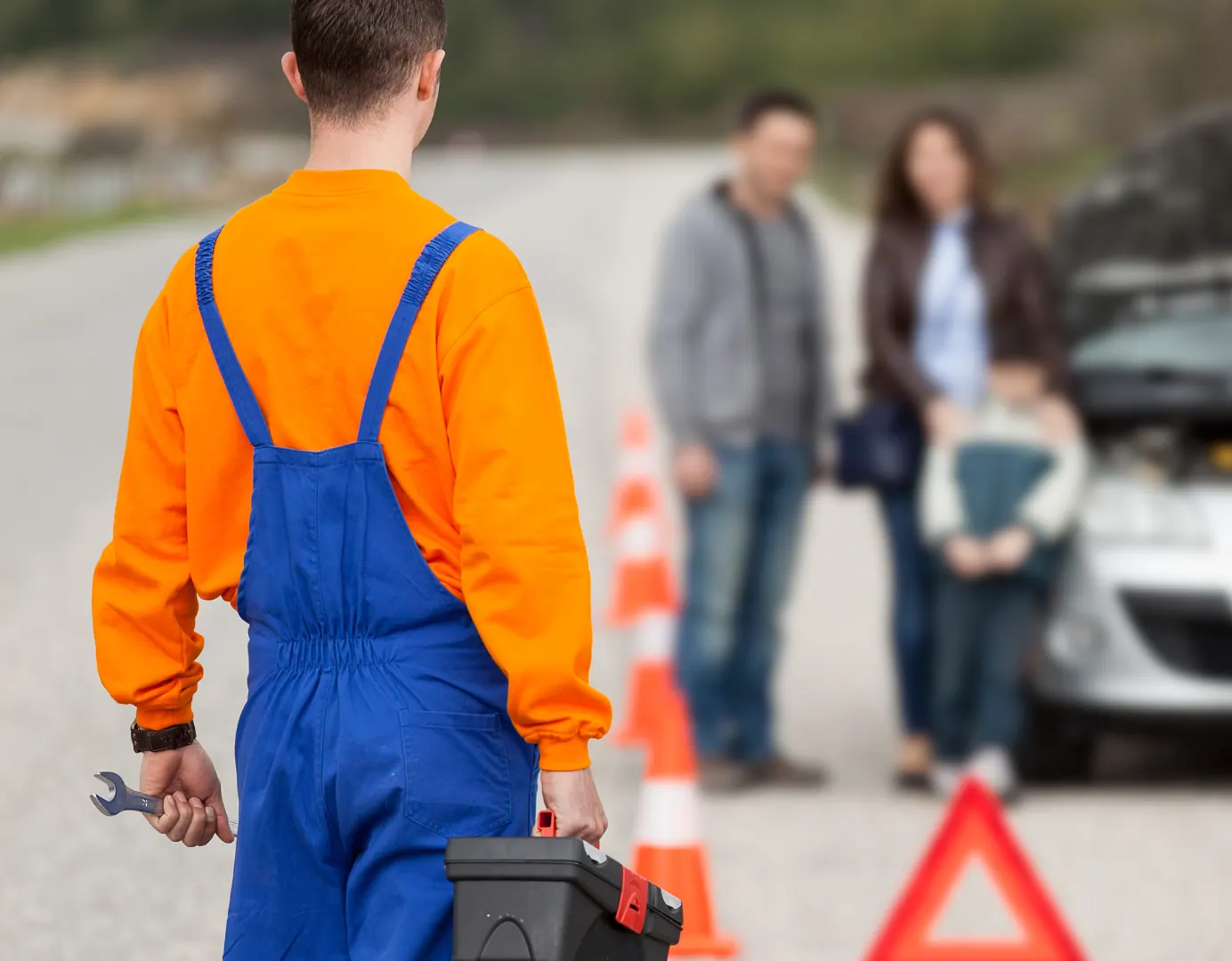 Roadside technician walking to a family with a broken-down car